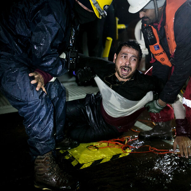 Ein syrischer Flüchtling wird von griechischen Helfern gerettet.