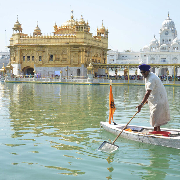 Ein Mann säubert das Wasser beim Goldenen Tempel in Amritsar (Indien)